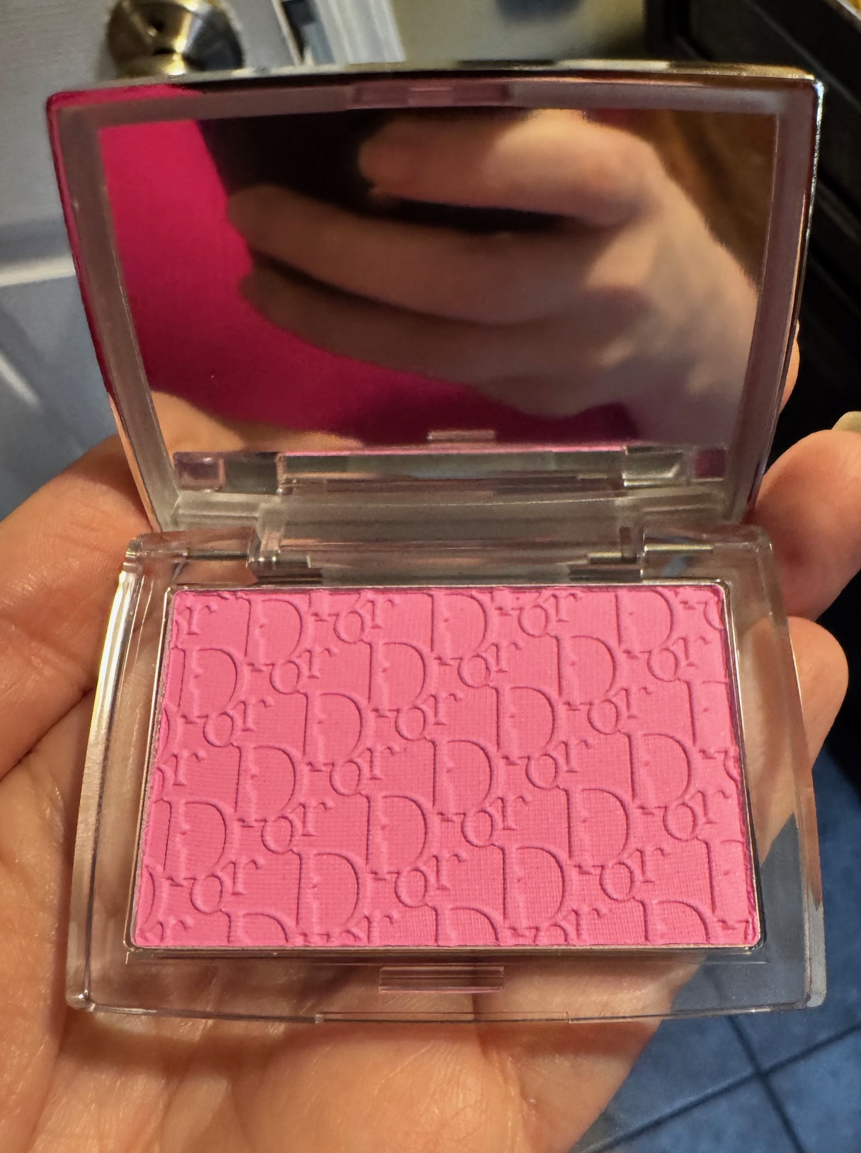 A woman's hand holding Dior pink blush