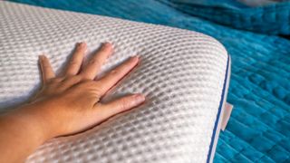 A hand pressing on the DreamCloud Best Rest pillow