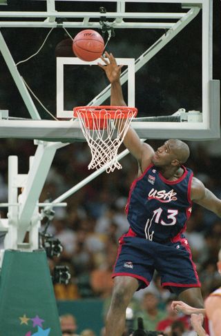 shaquille o'neal jumping for a basketball basket. the basketball is just above the basket in mid-air