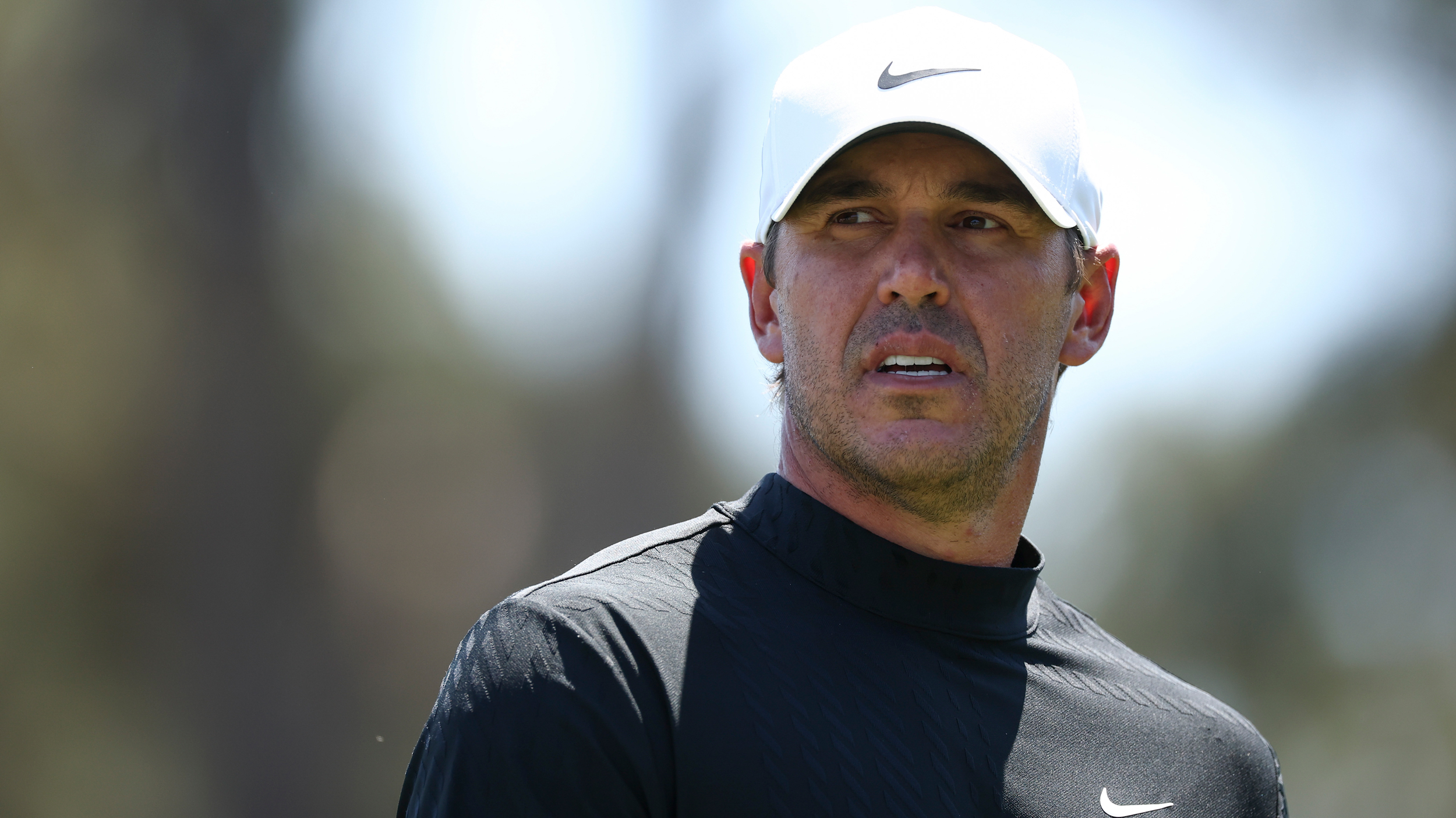 Brooks Koepka wearing a white Nike cap and black Nike mock turtleneck 