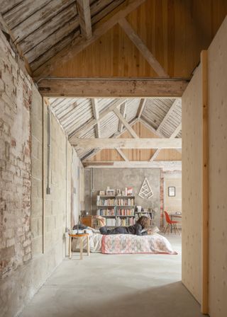 A corridor leads to the main bedroom, beneath retained and restored wooden beams, with a new concrete slab below