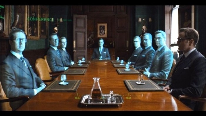 Screenshot from the movie Kingsman: The Secret Service showing off a VR conference.  Computer version of men sit at a table, next to one real person.