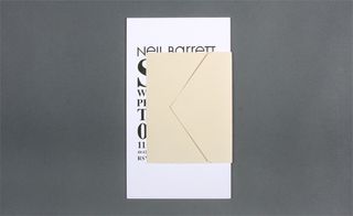 View of Neil Barrett's black and white invitation featuring an envelope pictured against a grey background. The envelope is closed hiding the details of the event