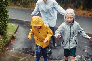 Kids with their mum all in waterproofs running for shelter in the rain