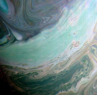 A false-color photo of Saturn depicts the planet's northern hemisphere as a swirling mess of green, blue and purple clouds