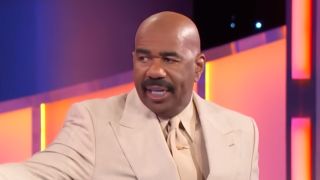 Steve Harvey in cream colored suit on Family Feud