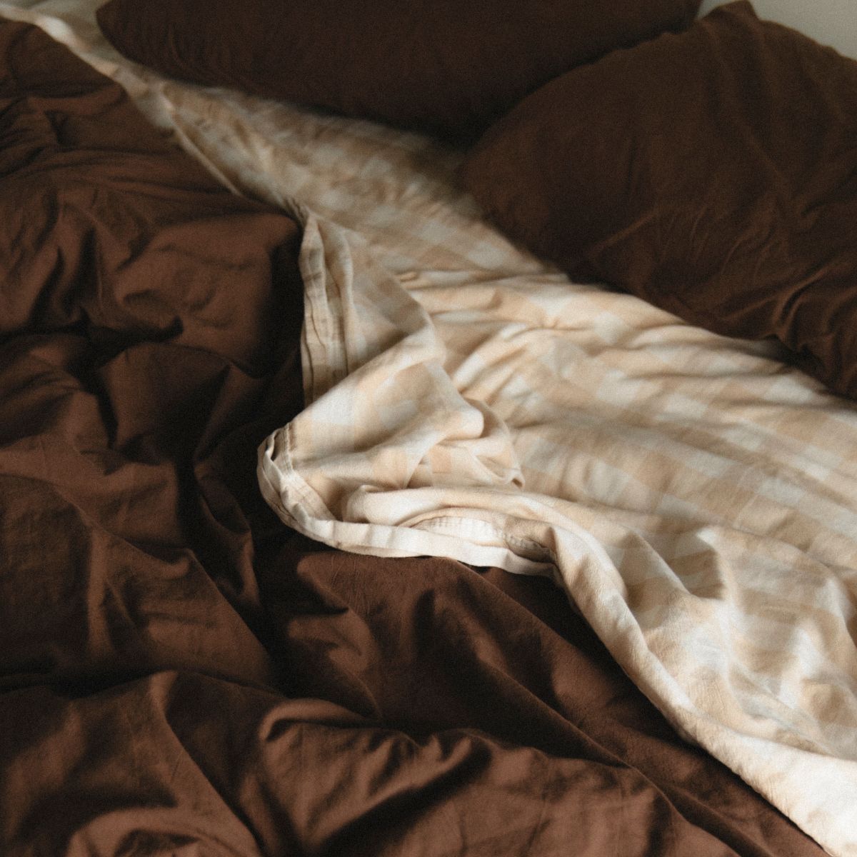 A chocolate brown duvet cover with gingham sheet