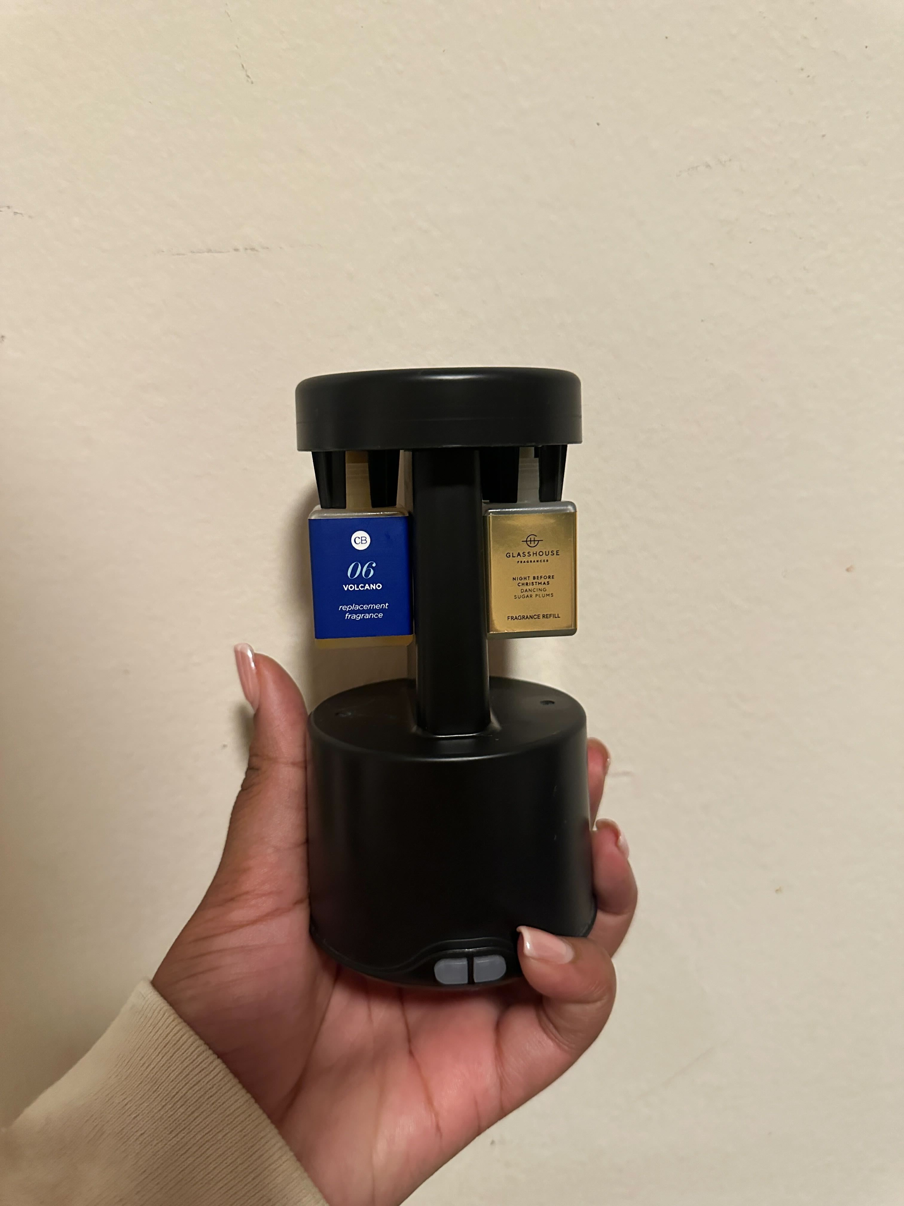 Ariel Baker holding a Pura Plus Diffuser with two scents from Capri Blue and Glasshouse Fragrances.