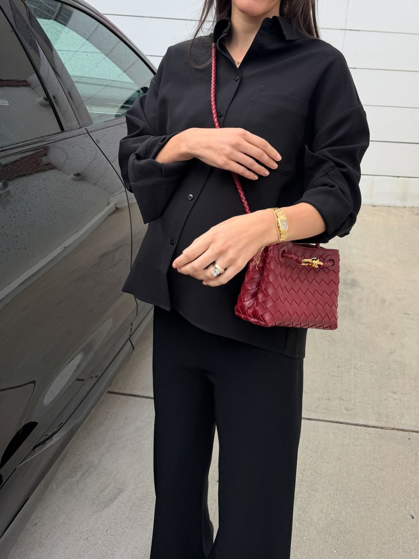 Ilana wears a black button-down shirt with black pants and the red andiamo mini bag.