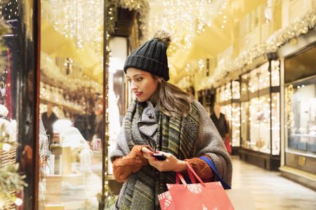 Woman is window shopping in decorated street.