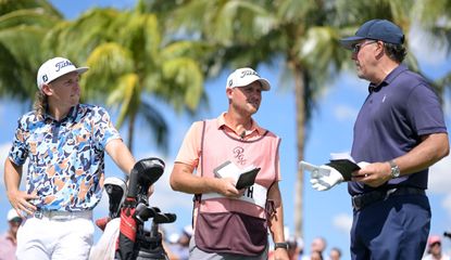 Smith and Mickelson chat on the tee while Smith's caddie looks on 