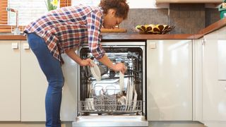 Woman unloading dish washer in kitchen