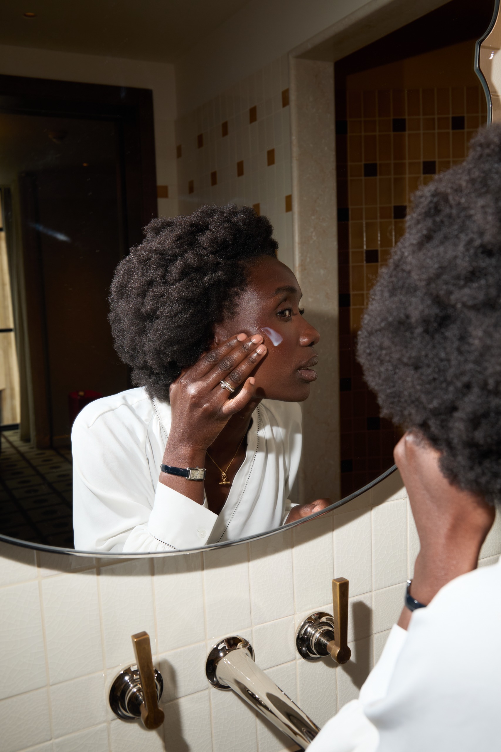 Mary Sommerlad applying the Sunday Riley Tidal Serum while looking in a mirror