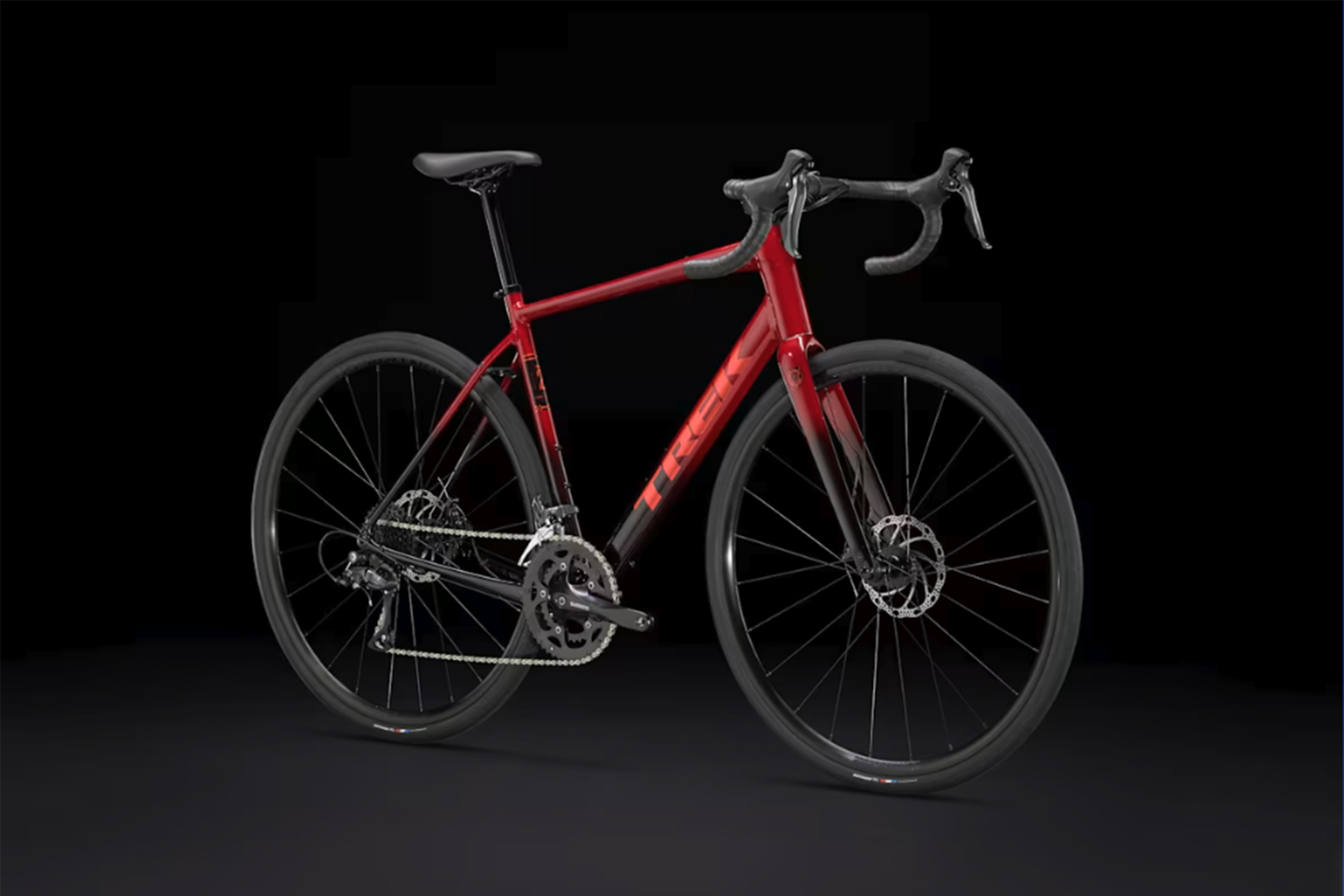 Trek Domane AL 2 in red and black disc brake model against a black and red background.