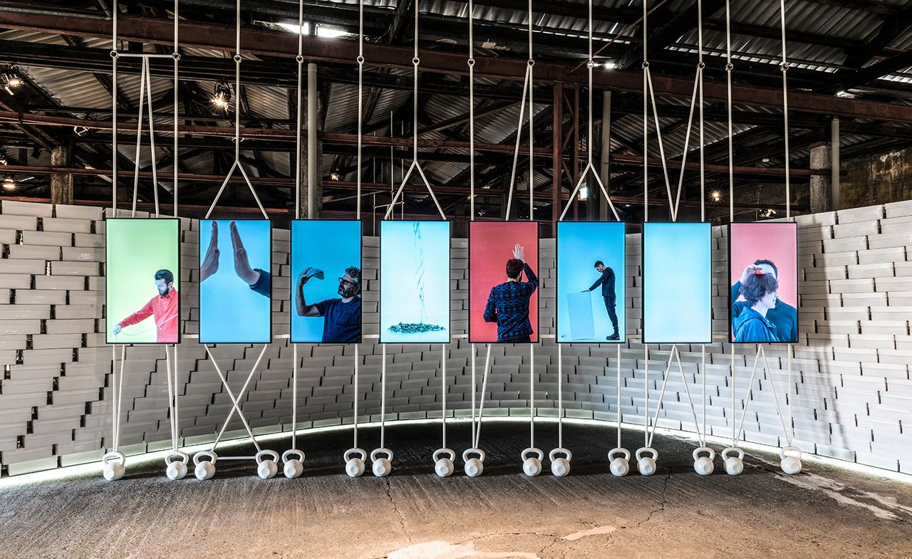 ’The Nature of Motion’ entrance display consists of neon background pictures framed in a black frame, with people on them in various poses representing motion.