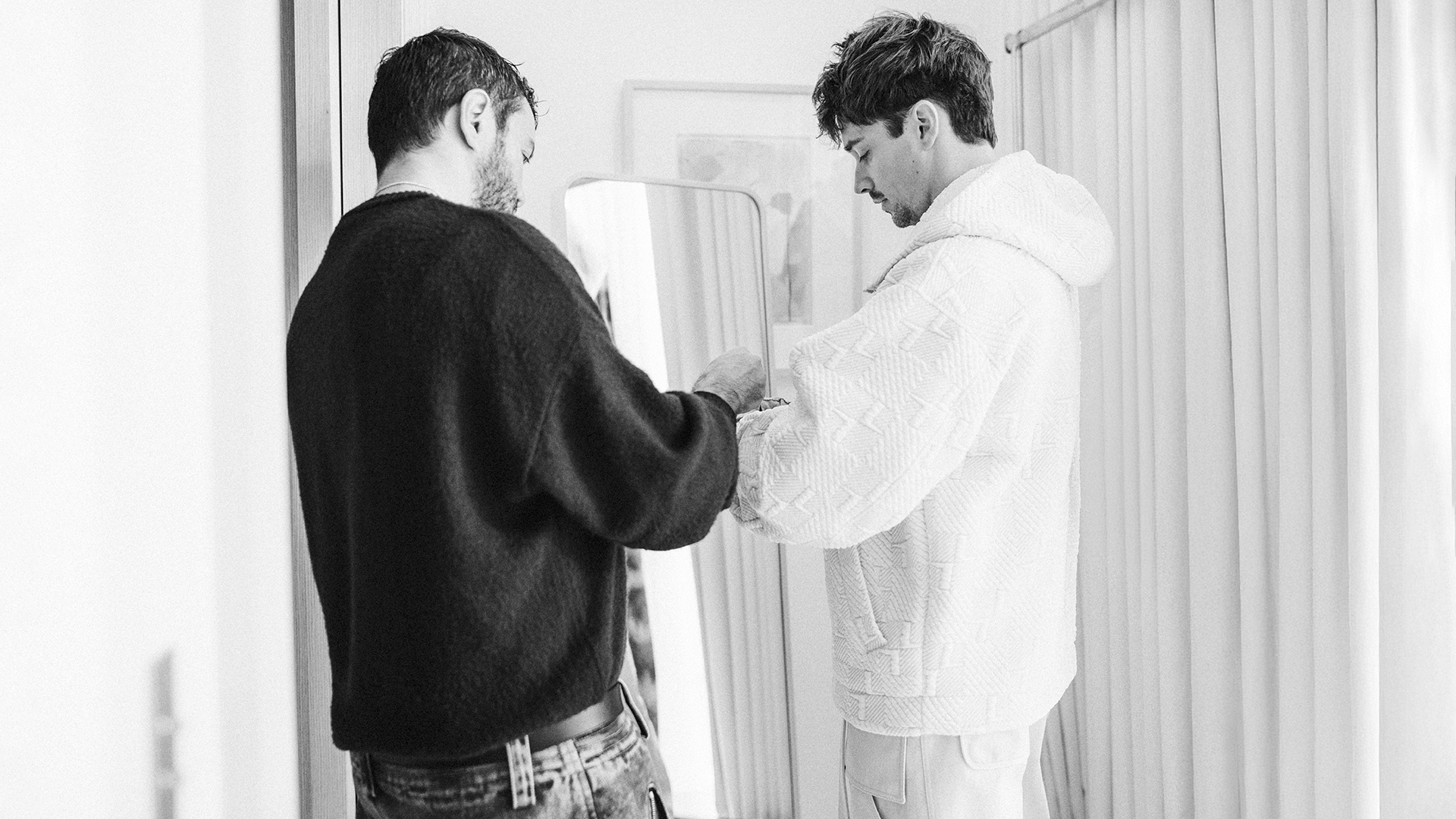 Scuderia Ferrari driver Charles Leclerc and Ferrari Style creative director Rocco Iannone work on new Ferrari x Charles Leclerc capsule collection in a black-and-white photograph.