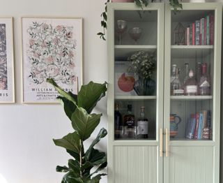 An ikea billy bookcase painted in a light sage green with brass handles