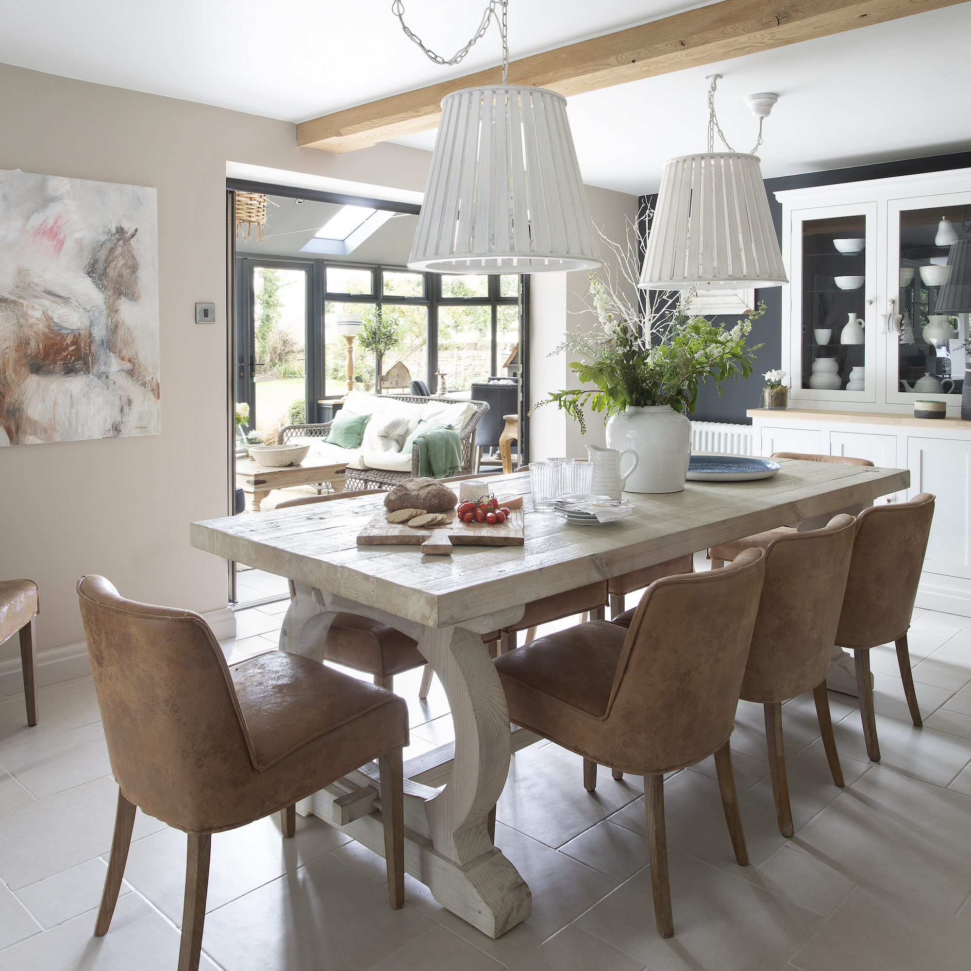 wooden dining table with leather dining chairs and large white pendant lights above