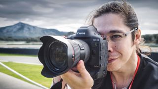 Man holding a Canon EOS-1D X Mark III with a mountain backdrop