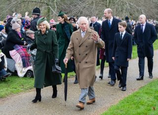 King Charles and Queen Camilla walking to church on Christmas wearing long coats with Prince William, Princess Kate and Prince George walking behind them and a crowd of fans