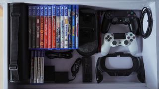 Video game collection in a drawer alongside a controller and wires packed neatly