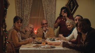 A family sits around a table in a dimly-lit room in the movie feast of the seven fishes