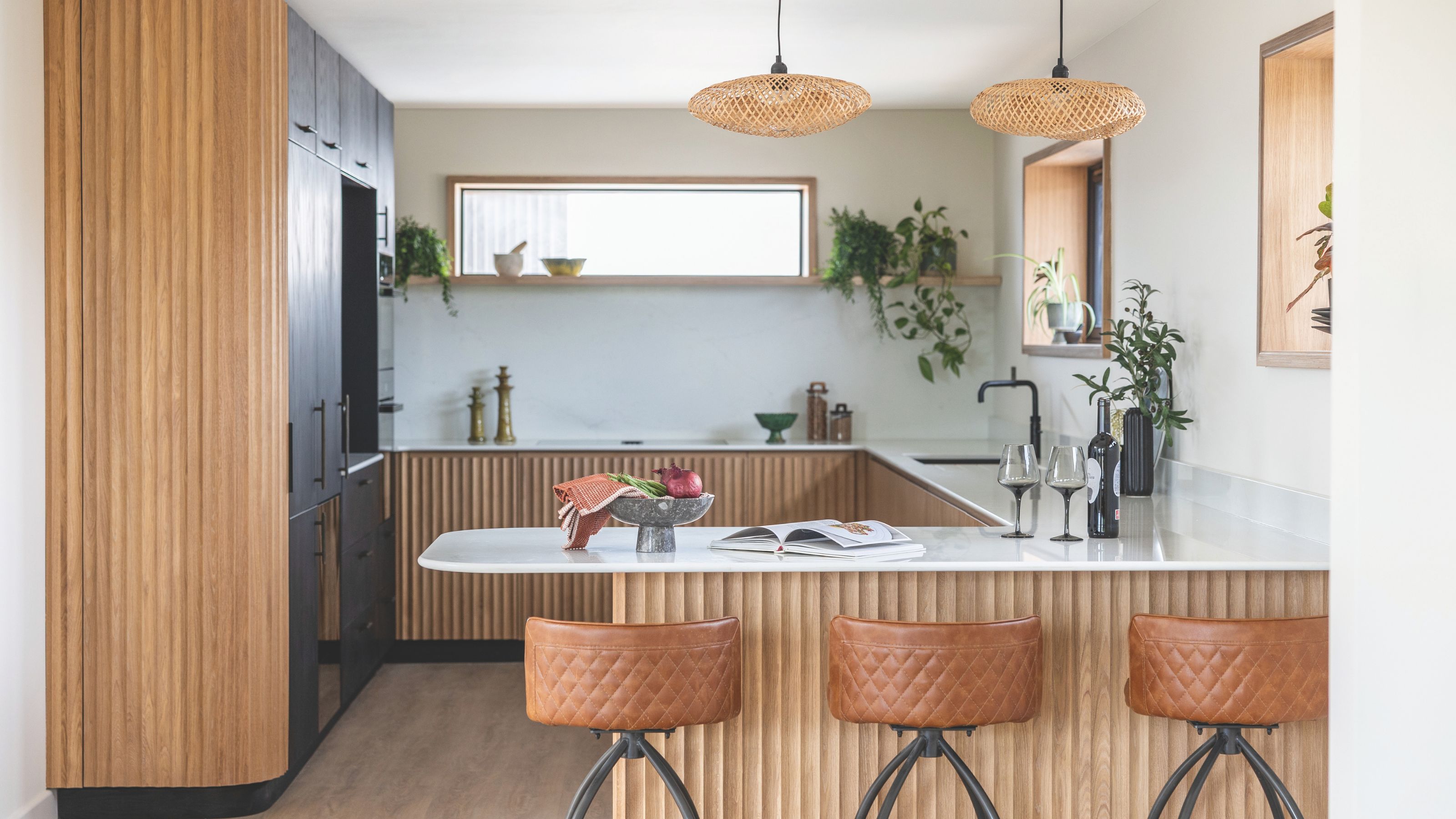 Japandi style kitchen with brown leather bar stools, marble island and wooden units