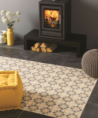 Traditional patterned floor tiles with rug effect in warm shades of gray and yellow, in front of roaring fire.