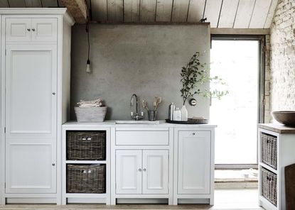 A farmhouse-style laundry room with white units and an exposed brick wall