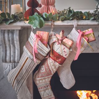 Mantlepiece with pink Christmas stockings hanging.