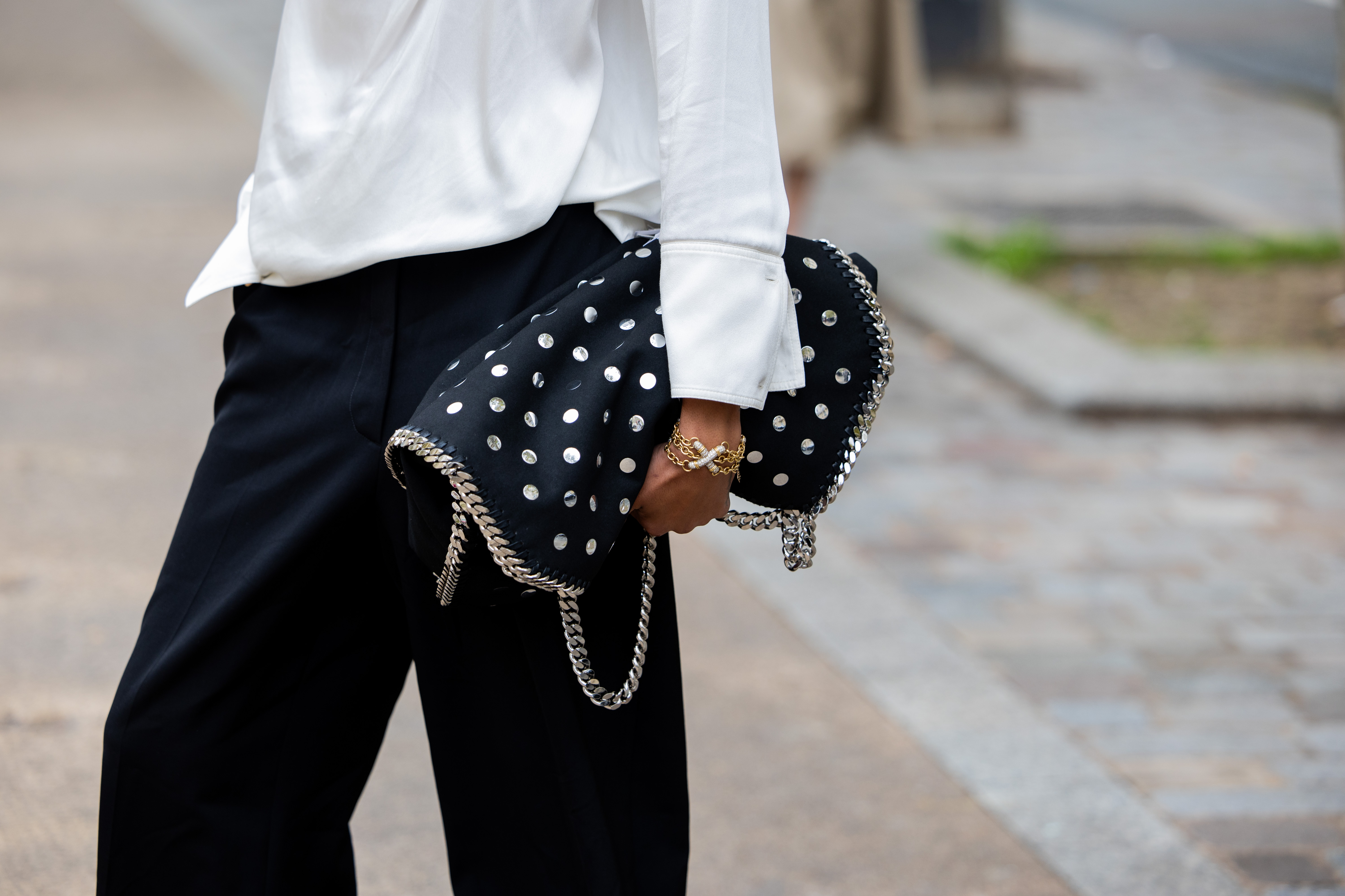 a woman carrying a studded black and silver stella mccartney bag