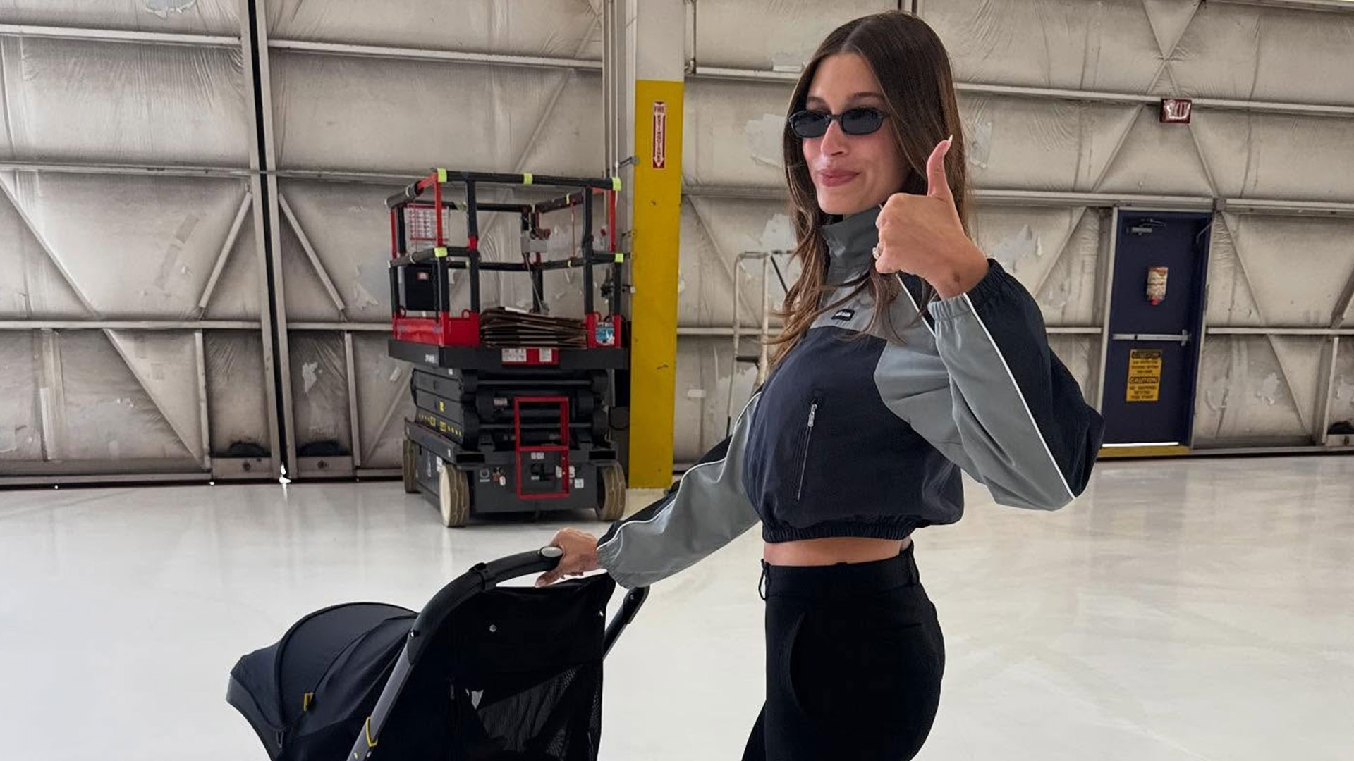 @haileybieber pushing stroller in cropped windbreaker and capri leggings 