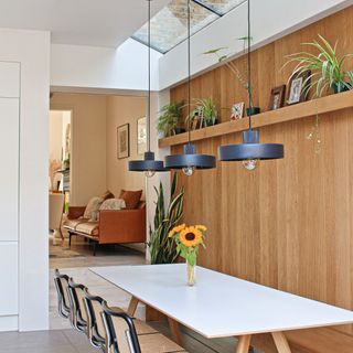 white kitchen table underneath black pendant lights