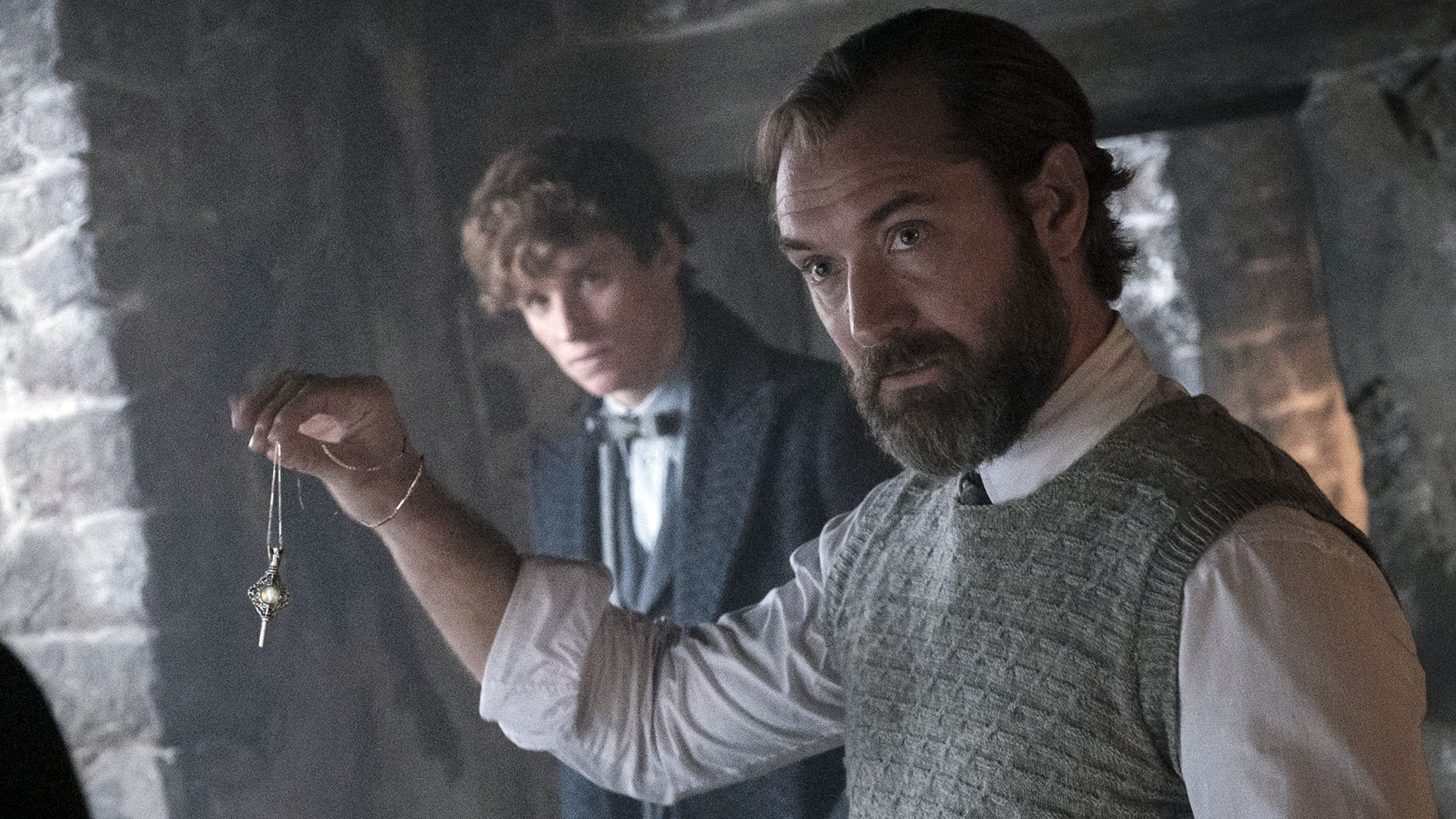 Dumbledore håller upp en amulett med Newt i bakgrunden i Fantastiska Vidunder 3