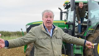 Jeremy spreads his arms out in front of a tractor