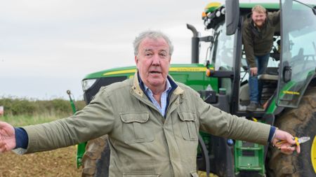 Jeremy spreads his arms out in front of a tractor