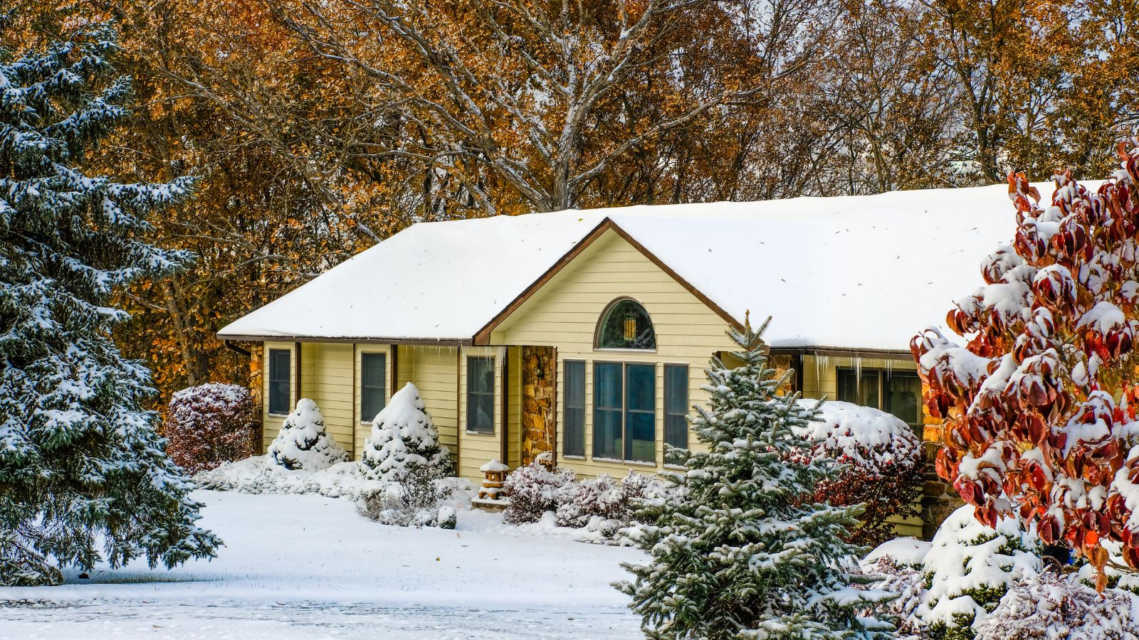 Suburban Midwestern house after first snowfall; fall foliage is still preserved; winter in Missouri