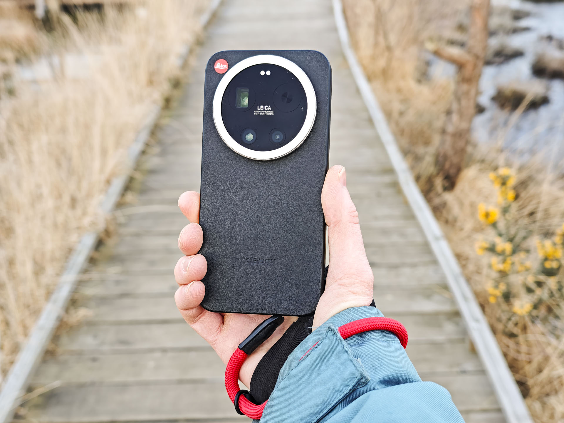 The Leica Leitzphone in person's hand with a wooden boardwalk backdrop