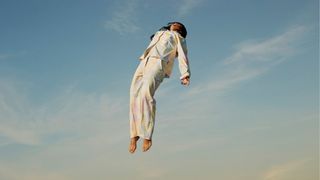 woman wearing pyjamas falling through the air in the sky