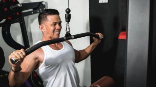 Man performing wide-grip lat pull-down in gym