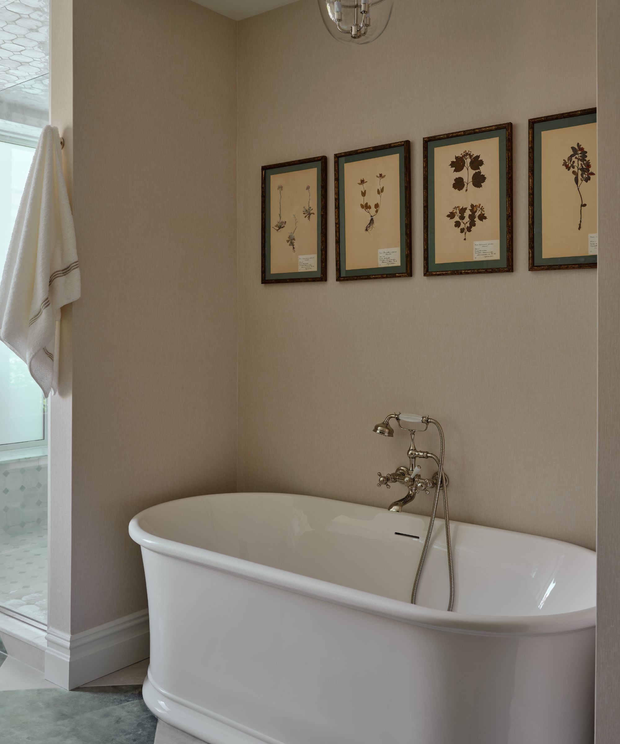 a serene soft blush bathroom with green checkerboard tiled floor, a large freestanding tub and floral artwork