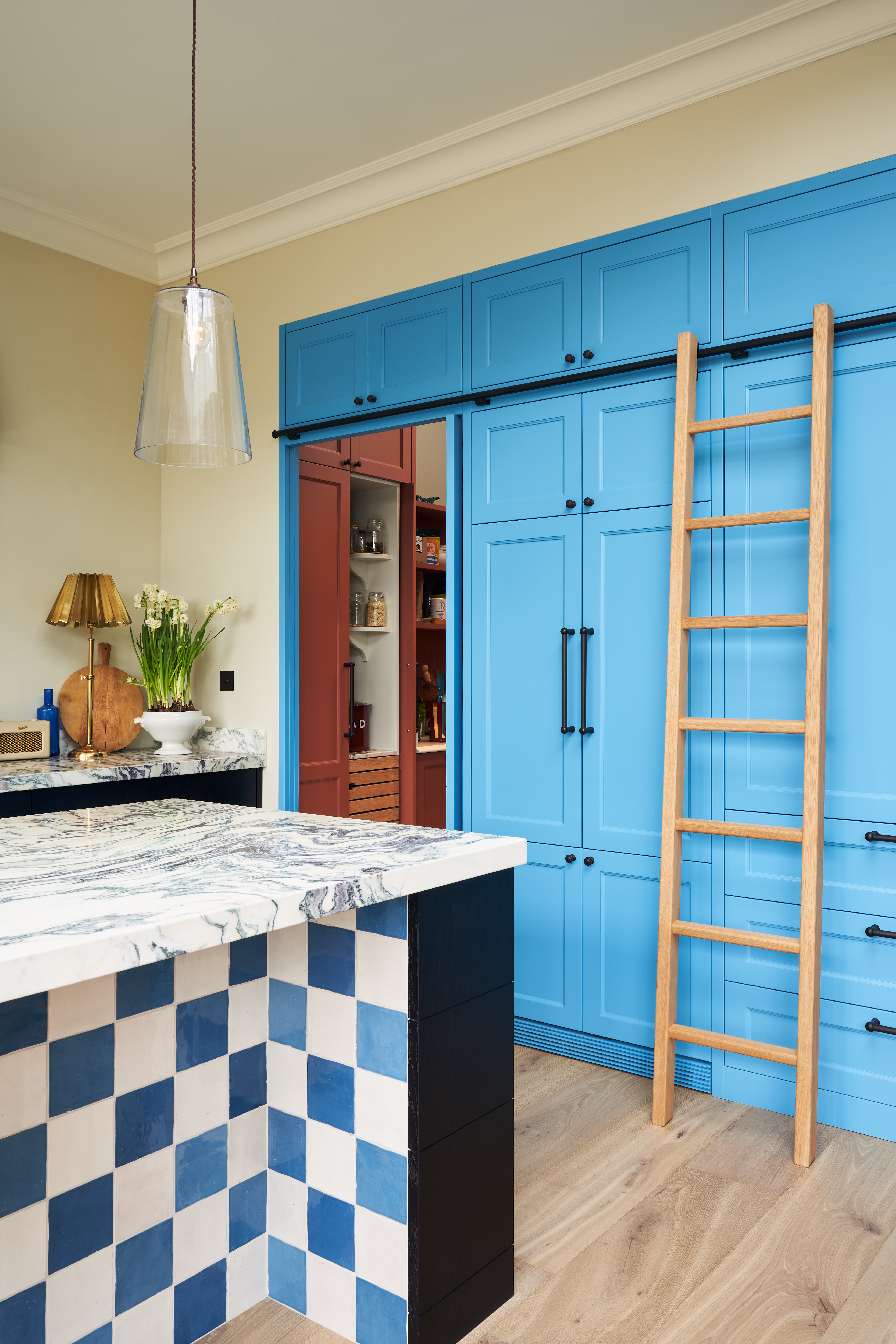 Bright blue kitchen cabinetry with checkerboard tiling on the island