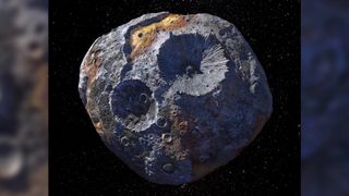 A large gray space rock with large craters on the surface and patches of brown material. 