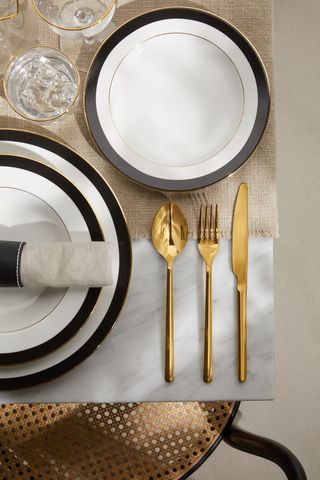 gold knife fork and spoon on a set table with black and gold plates
