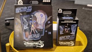 Two pins contained in carboard packaging on a golden side table