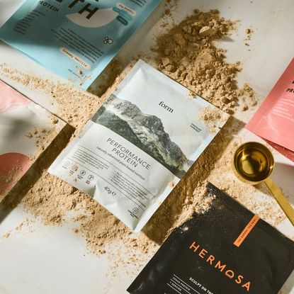 A flat lay of some of the best protein powders for women, including travel sachets from Form Nutrition, Hermosa, Innermost, MyProtein and more