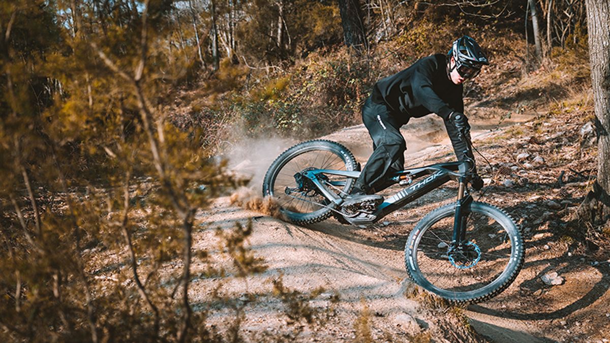 A man drifting the Thok Gram e-MTB round a dusty corner