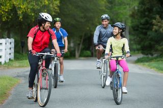 The best bicycle insurance will offer discounts for more than one bike. This image shows a family of four riding their bikes two by two in a road