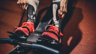 Hands tightening straps around shoes in rowing machine footplates