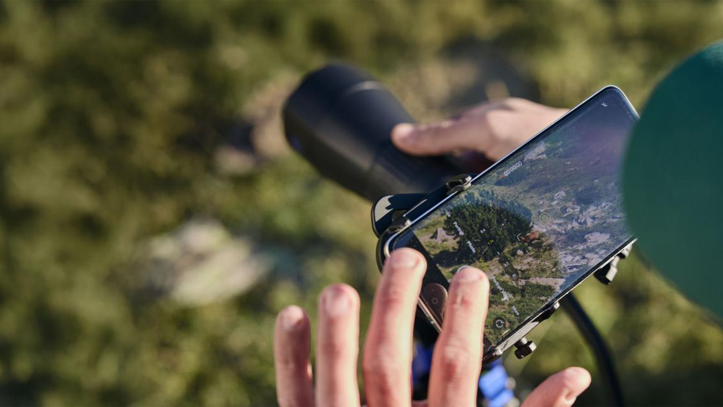A top-down look at someone using a smartphone attached to a spotting scope to take a picture.